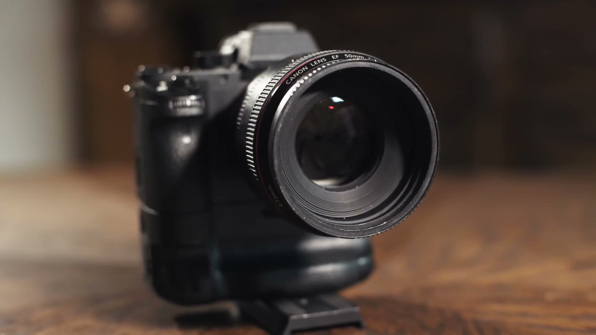 A Sony mirrorless camera with a Canon 50mm lens adapted to it, sitting on a wooden table
