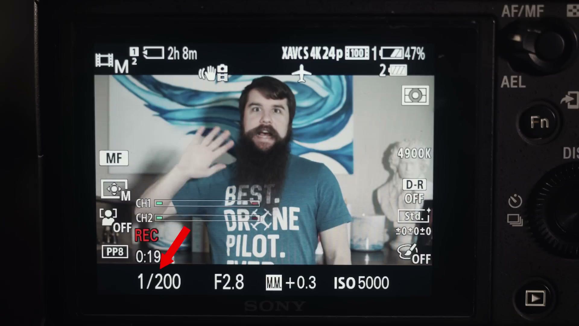 A camera rear screen with the shutter speed reading 1/200 highlighted by a red arrow, at F2.8 and ISO 5000