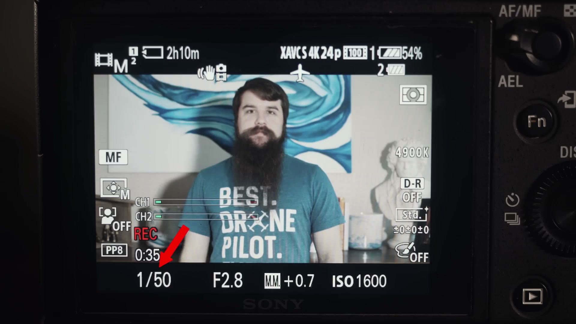A camera rear screen recording XAVC S 4K 24p with the shutter speed reading 1/50 highlighted by a red arrow, at F2.8 and ISO 1600