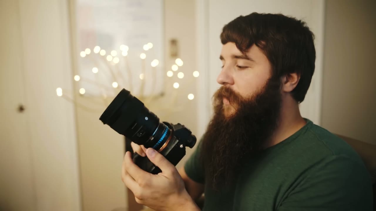 Matt examining a Sigma Art lens adapted to the Sony a7S II, string lights glowing behind him