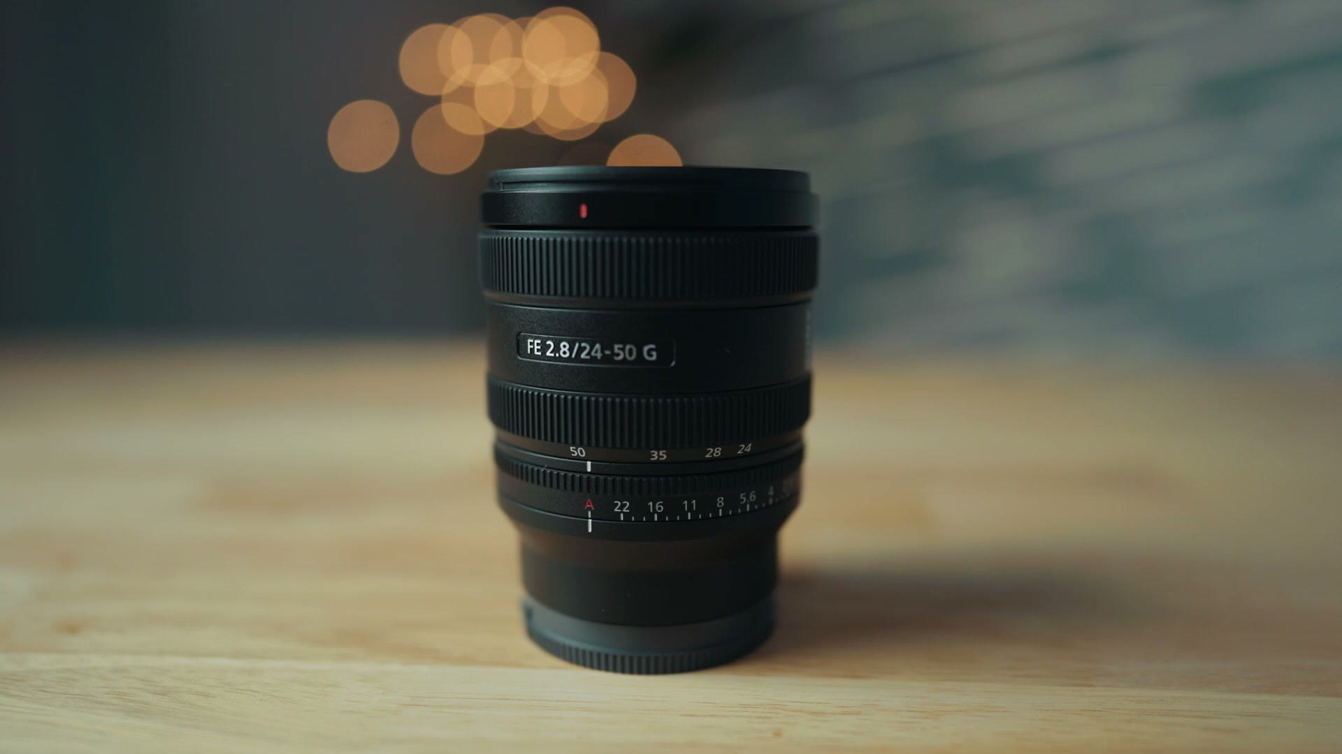 Sony 24-50mm f/2.8 G lens standing on a wooden table