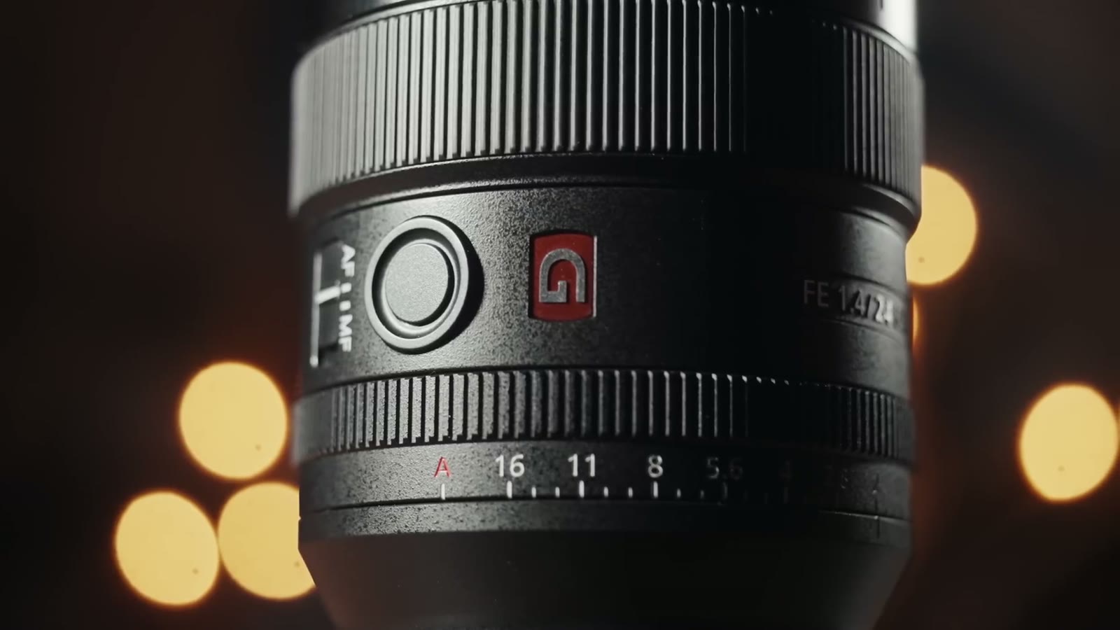 A close up of the Sony 24mm GM showing the AF and MF switch, the red G badge and the aperture ring marked 16, 11, 8, with bokeh balls behind