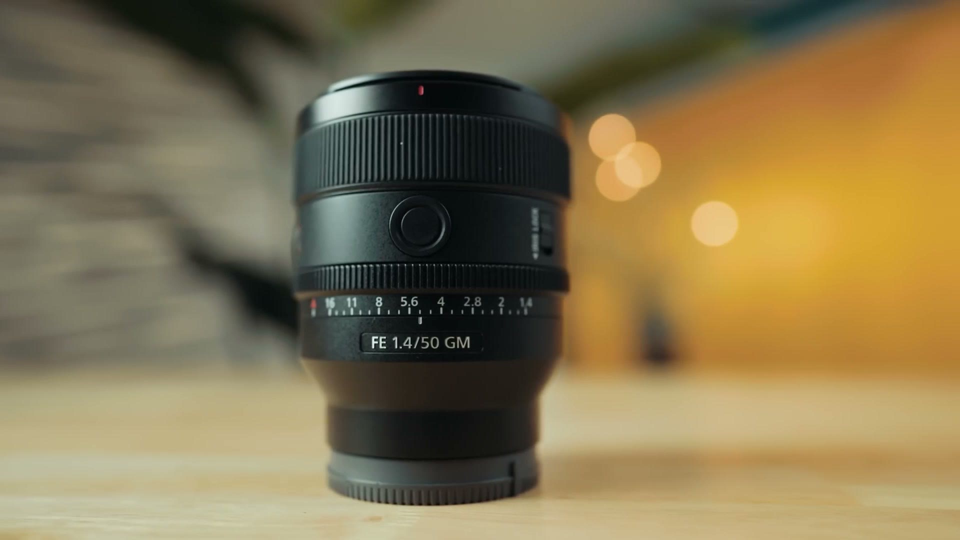 The Sony 50mm f/1.4 GM standing on a table with bokeh behind it