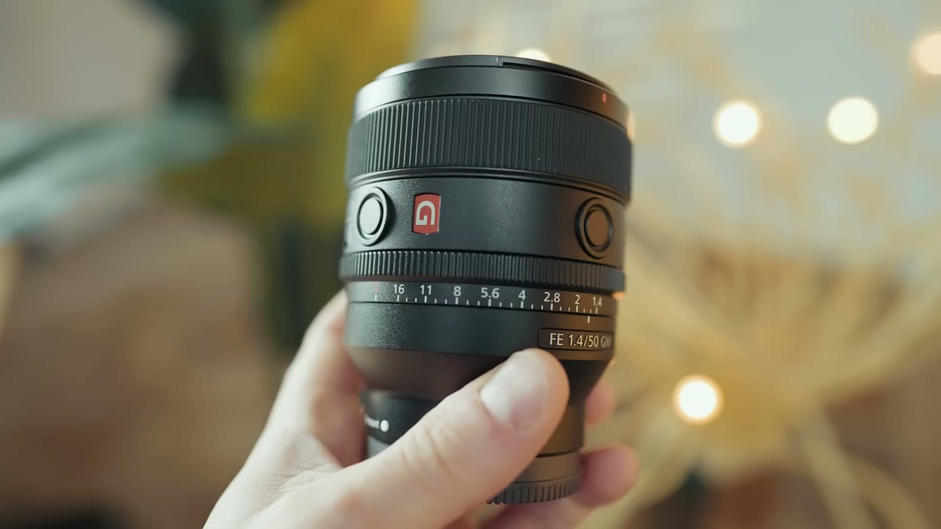The Sony 50mm f/1.4 GM held up with bokeh lights behind it