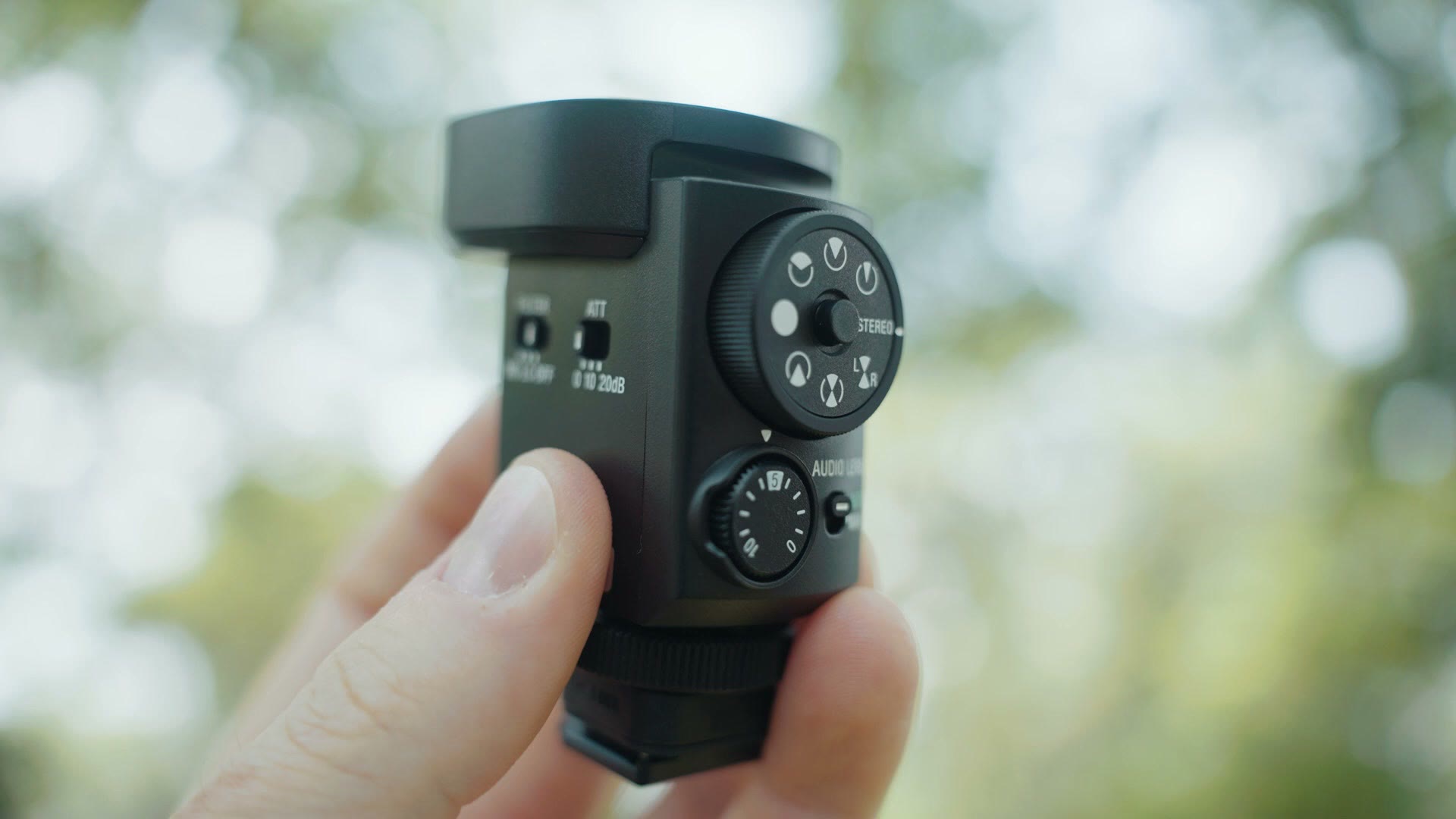 The Sony ECM-M1 microphone held in one hand showing the large directionality dial on the back
