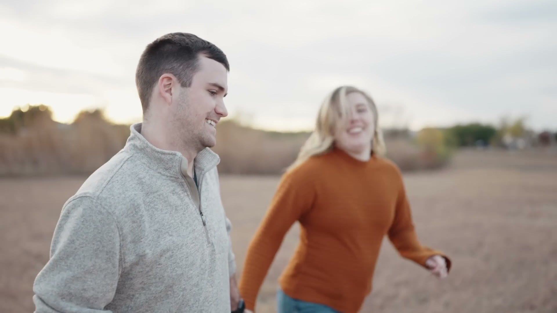A couple running through a field, both faces sharp, filmed handheld at 120 frames per second