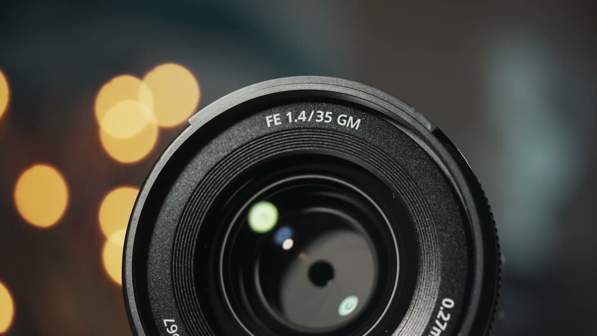 Front element of the Sony FE 1.4/35 GM lens with warm bokeh behind it