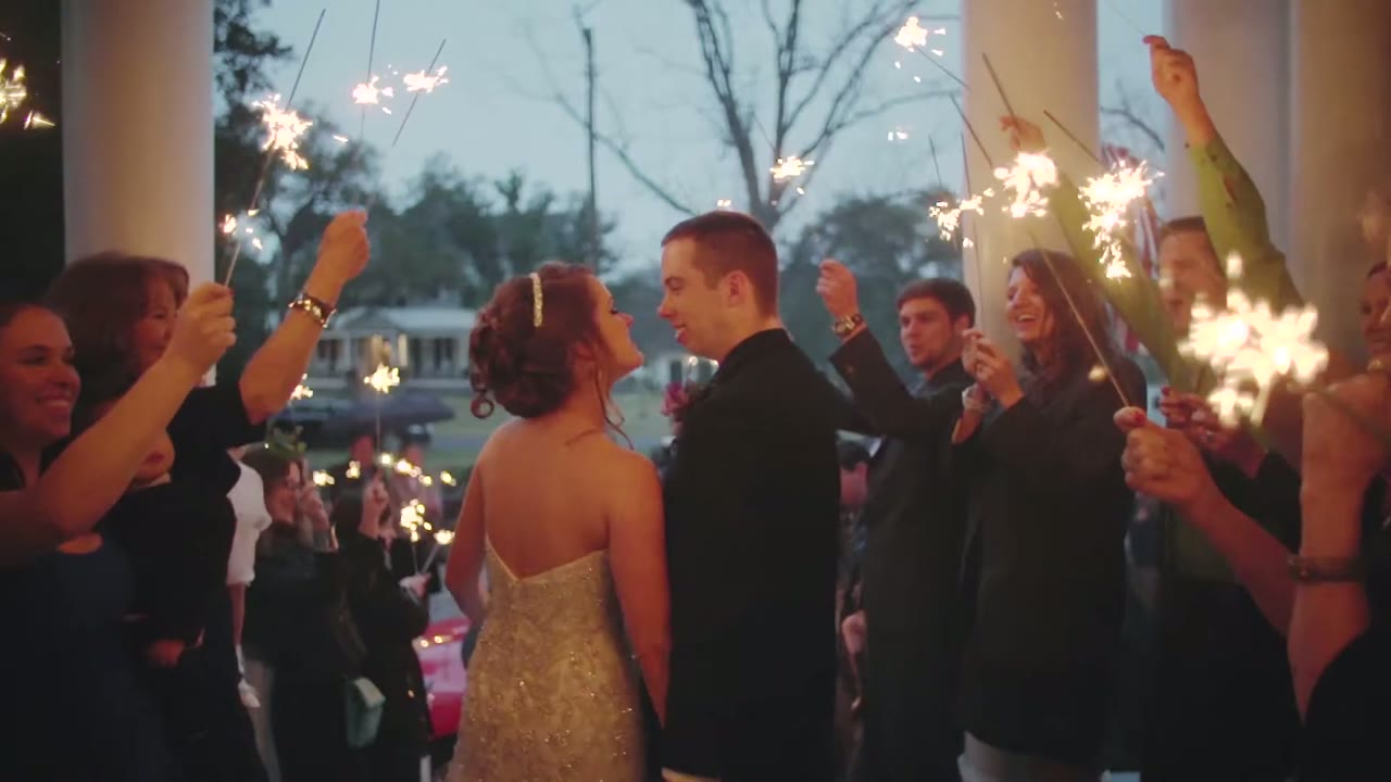 Sparkler exit under the front porch columns, bride and groom walking through guests holding lit sparklers at dusk