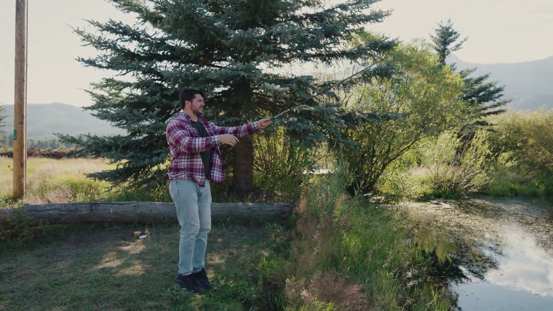 A person casting a fishing pole into a pond