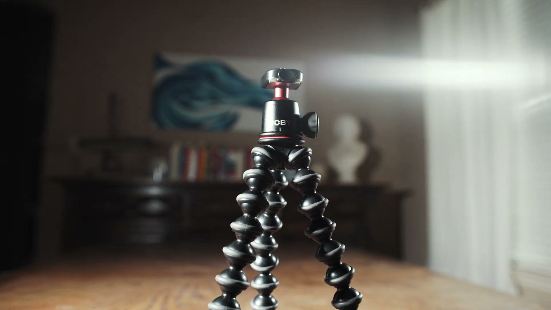 A Gorillapod on a table with a small ball head mounted on top of it