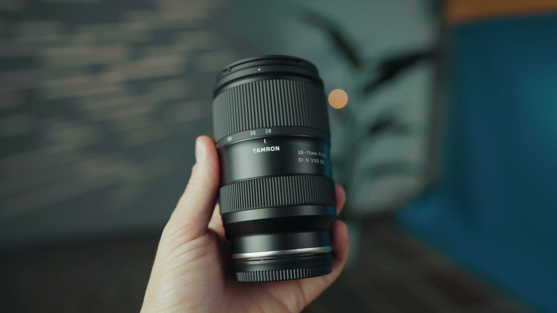 The Tamron 28-75mm G2 lens held in one hand