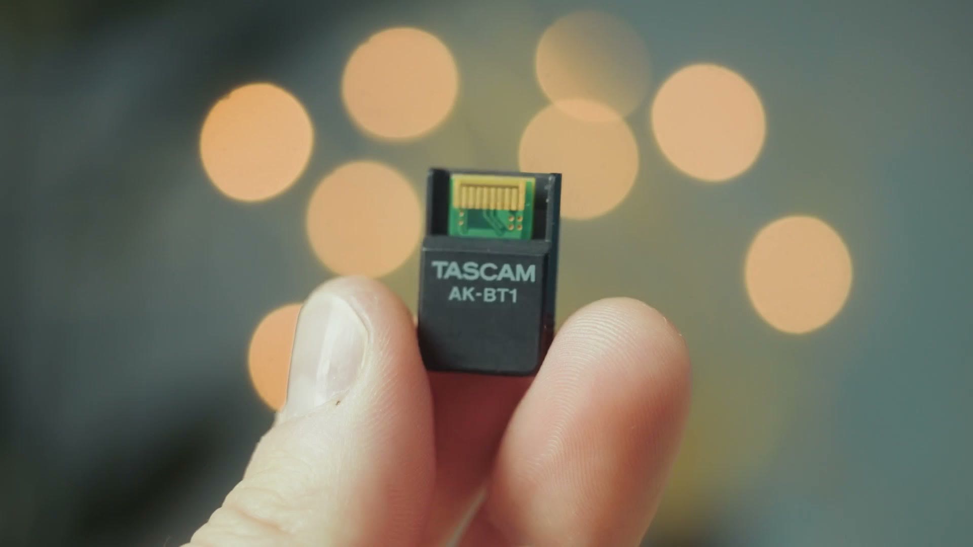 The Tascam AK-BT1 Bluetooth adapter held between two fingers