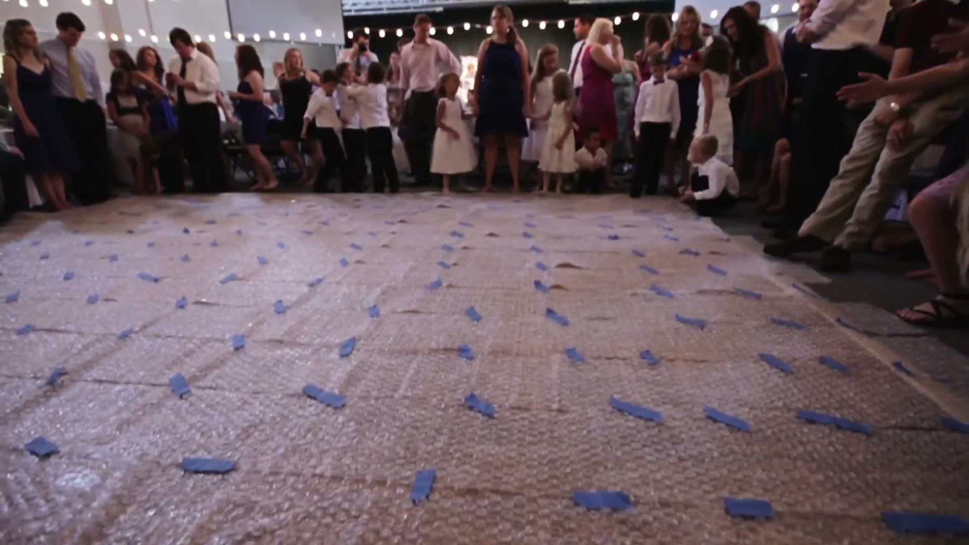A brick walkway outside the church covered in scattered confetti with wedding guests lined up along both sides under string lights