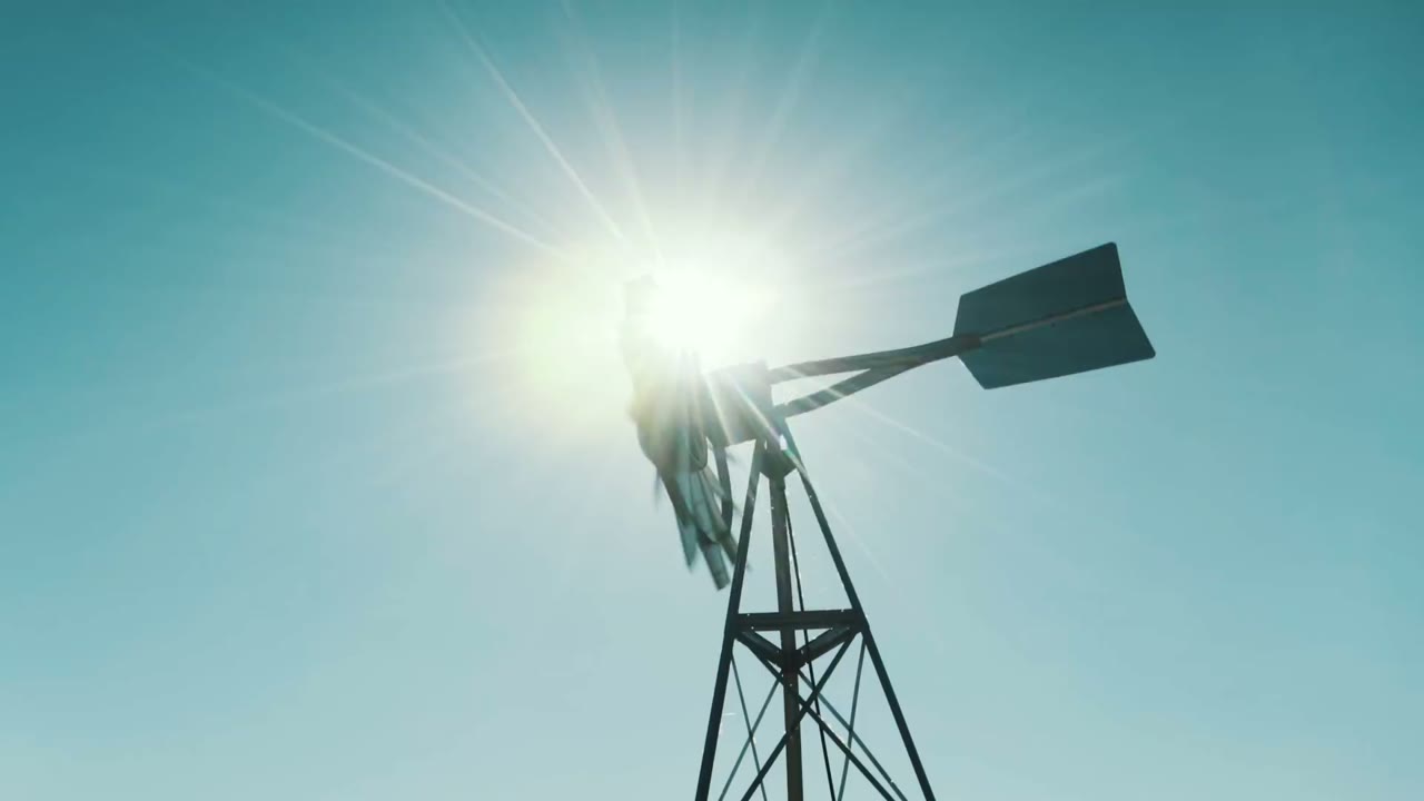Silhouette of a windmill against a bright sunburst sky over the Texas hill country