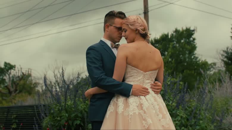The bride and groom holding each other forehead to forehead in a bed of lavender under a heavy grey sky