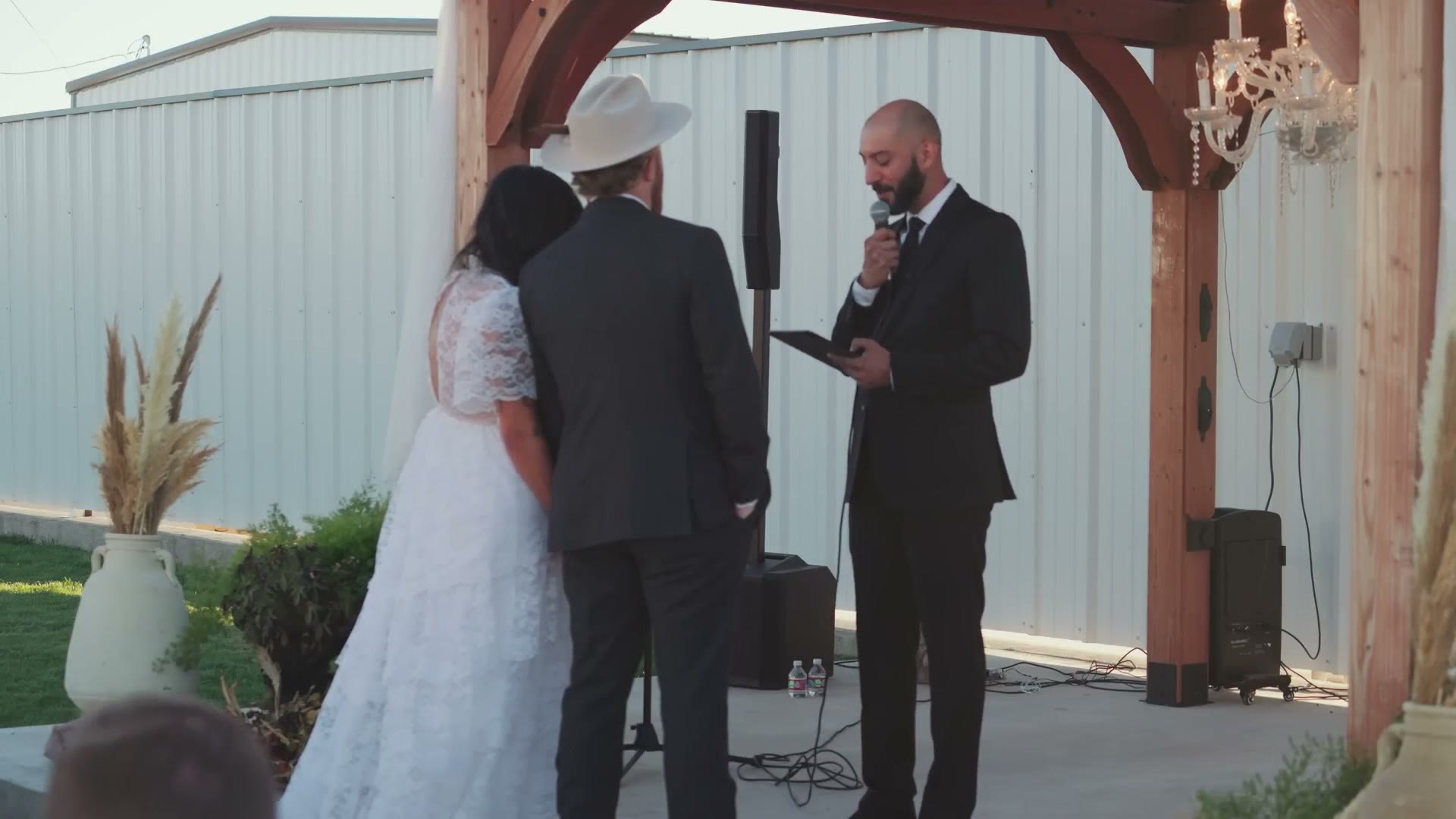 Wide shot of a wedding ceremony under a wooden arbor