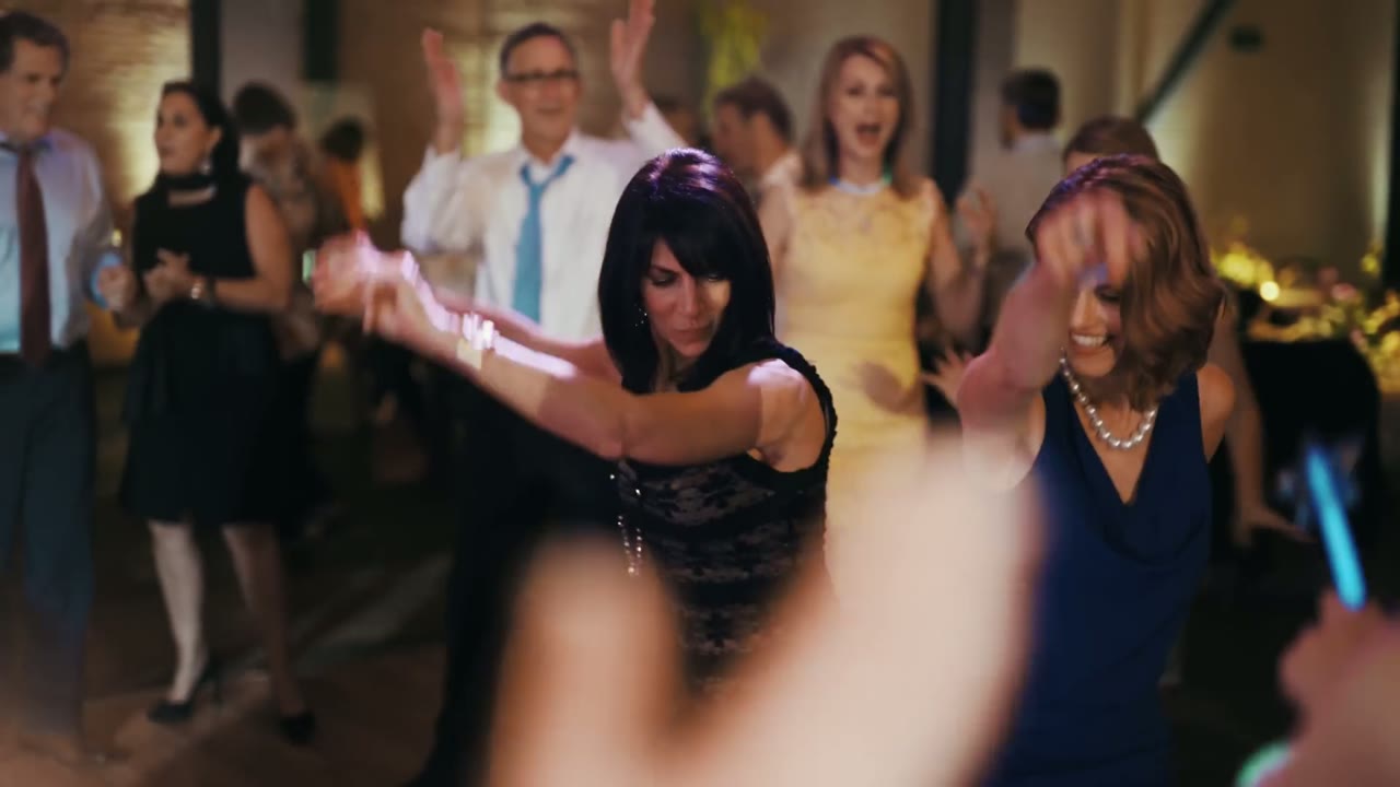 Guests dancing with their hands in the air on a warmly lit dance floor
