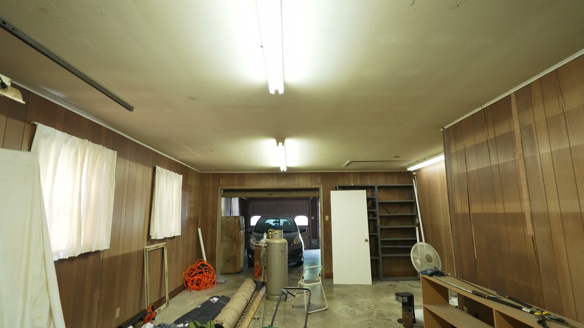 The garage workshop before renovation, with cheap wood paneling and a concrete floor