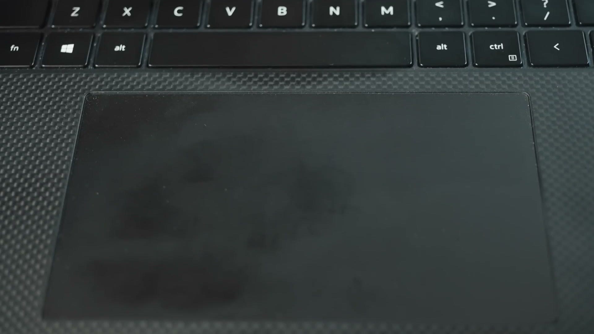 Close-up of the XPS 17's oversized glass trackpad below the keyboard, set into the carbon fiber palm rest
