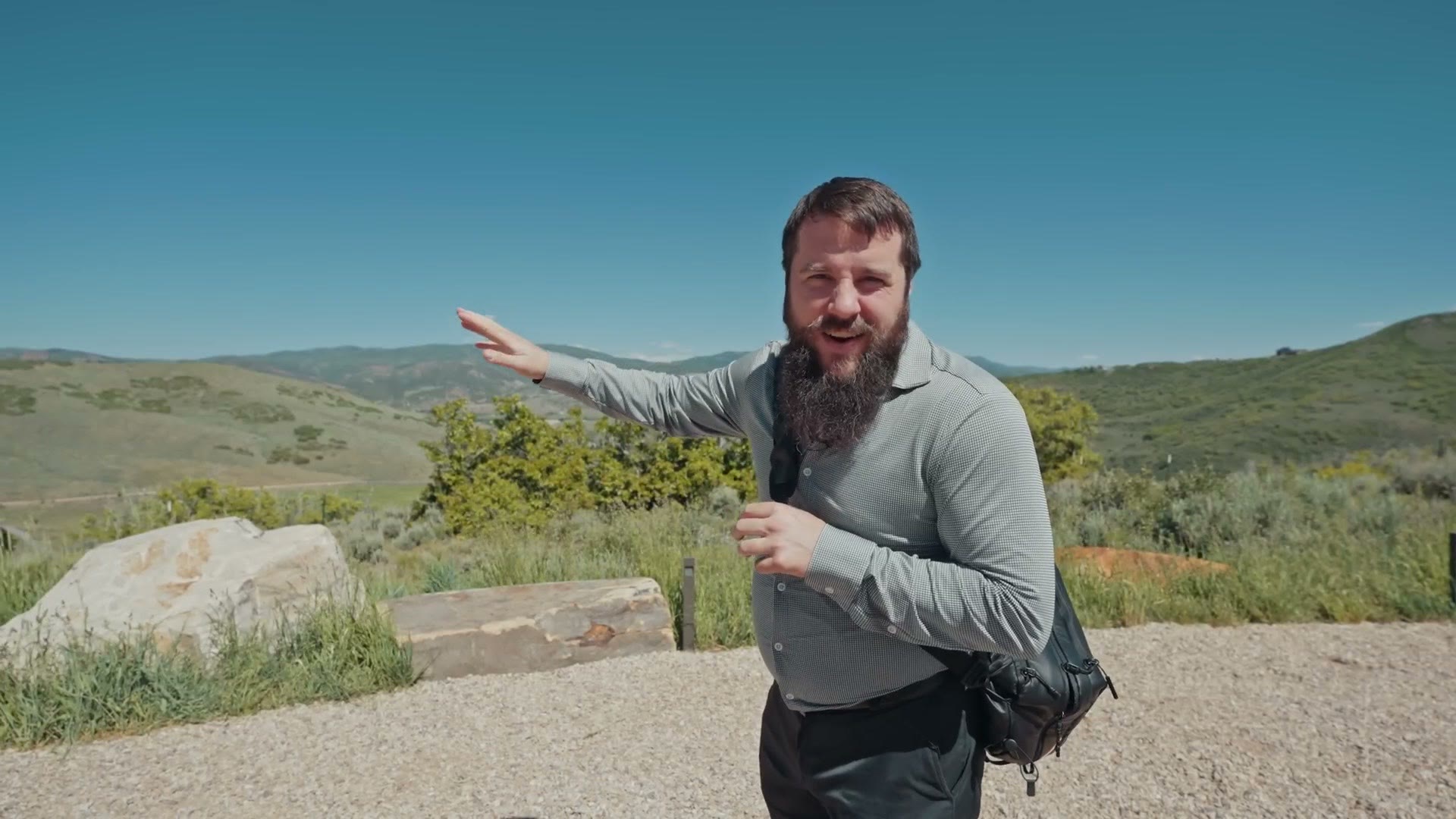 Matt gesturing toward a mountain overlook with the Utah hills behind him