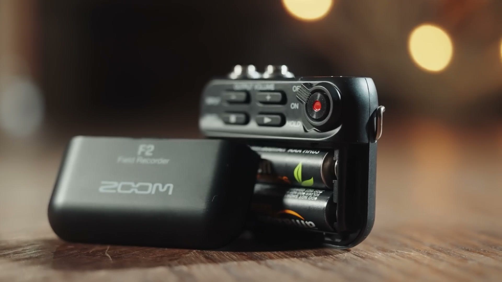 The Zoom F2 with its battery door open showing two AAA batteries