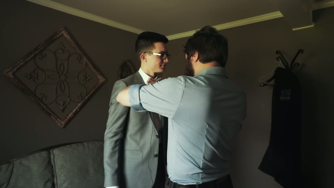 Matt, seen from behind, adjusting the shoulder of the groom's suit jacket