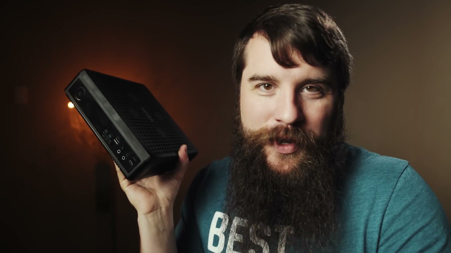 The black Zotac Magnus mini PC held up in one hand, showing how small the whole computer is