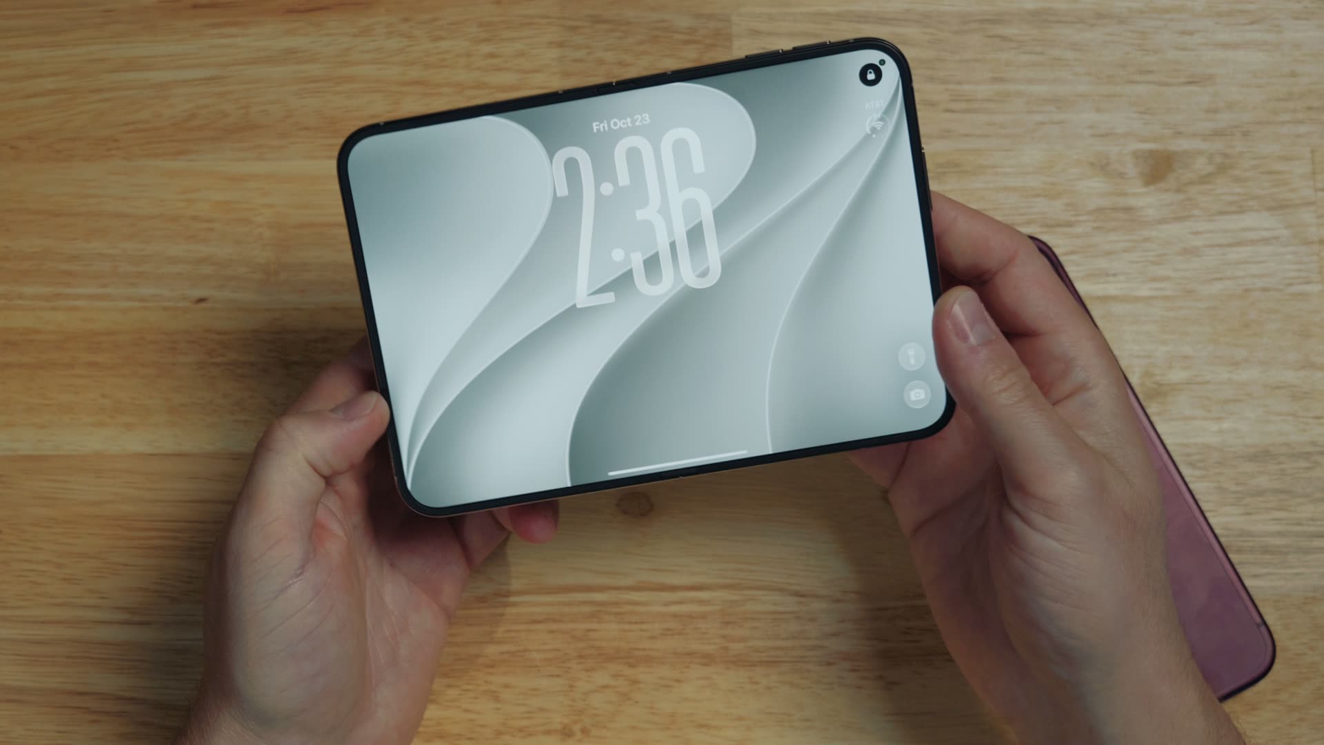 The iPhone Duo unfolded in two hands, showing its large inner screen on the lock screen